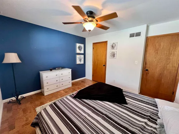 a bedroom with a bed and a lamp on dresser