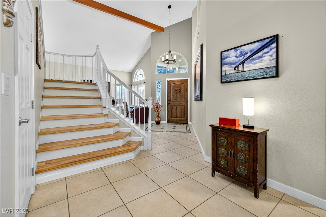 980 Upper Meadows Place Henderson, NV 89052 - Photo 13 of 58 Foyer with light tile patterned floors, beamed ceiling, high vaulted ceiling, stairs, and a chandelier