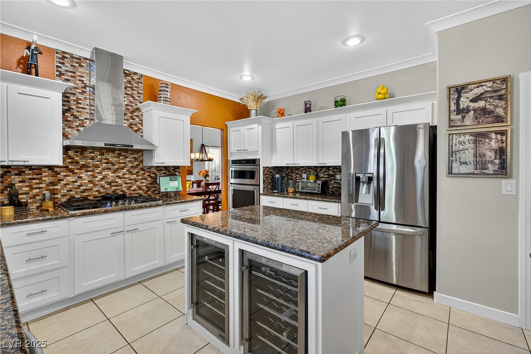 980 Upper Meadows Place Henderson, NV 89052 - Photo 20 of 58 Kitchen with dark stone countertops, tasteful backsplash, light tile patterned floors, stainless steel appliances, and ornamental molding