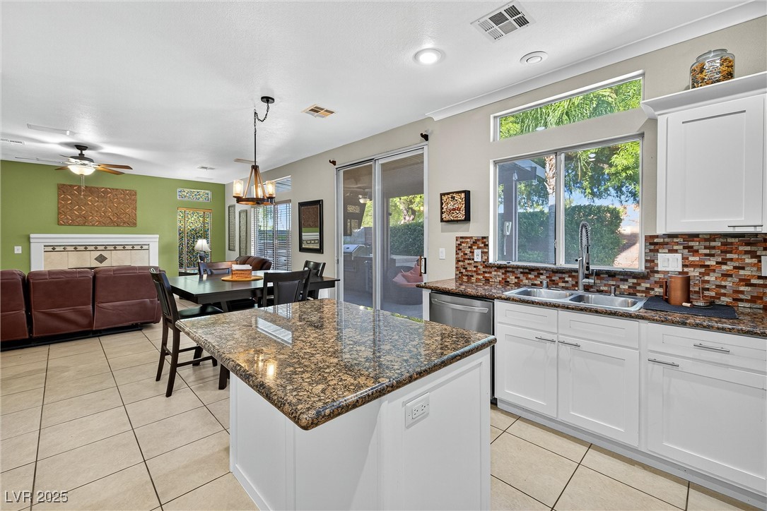 980 Upper Meadows Place Henderson, NV 89052 - Photo 58 of 58 Kitchen featuring hanging light fixtures, white cabinetry, light tile patterned floors, decorative backsplash, and open floor plan