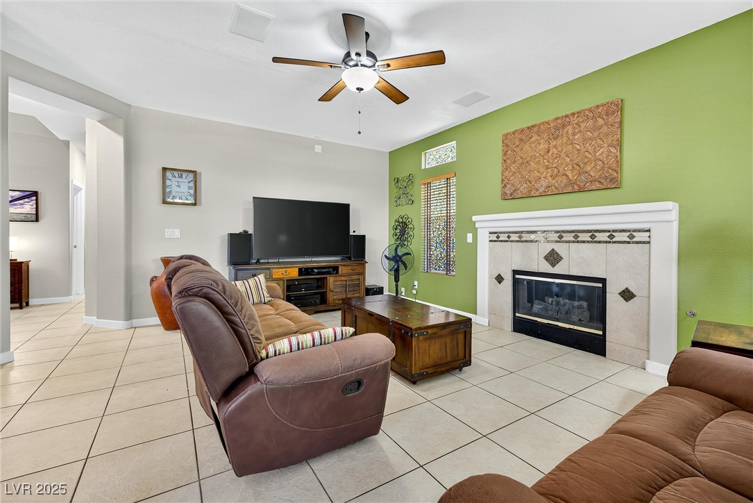 980 Upper Meadows Place Henderson, NV 89052 - Photo 23 of 58 Living area featuring light tile patterned flooring, a ceiling fan, and a tiled fireplace