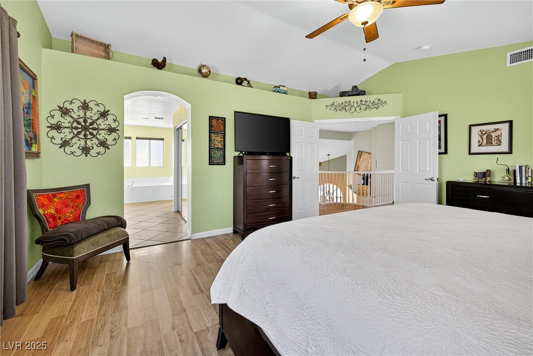 980 Upper Meadows Place Henderson, NV 89052 - Photo 32 of 58 Bedroom with light wood-style flooring, arched walkways, vaulted ceiling, and ceiling fan