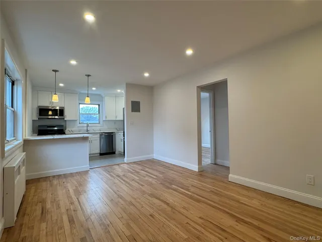 a view of kitchen with kitchen island wooden floors granite counter tops and white appliances