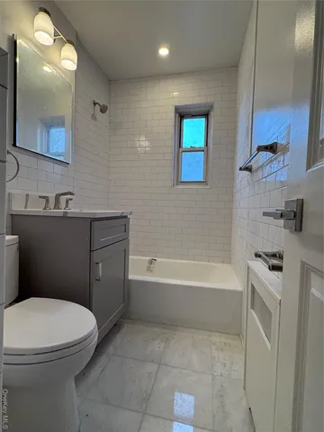 a bathroom with a toilet a sink a mirror a bathtub and vanity