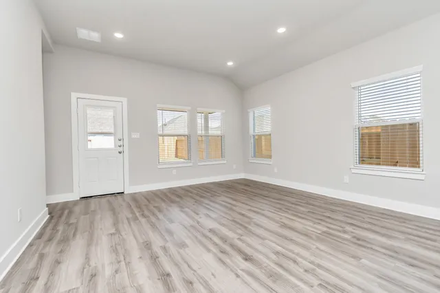 an empty room with wooden floor and windows