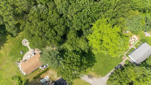 an aerial view of a residential houses with outdoor space and trees all around