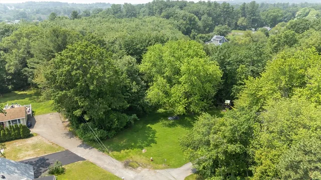 an aerial view of residential house with outdoor space and trees all around