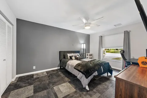 a spacious bedroom with a bed and a dresser next to a window