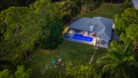 an aerial view of residential houses with outdoor space and trees