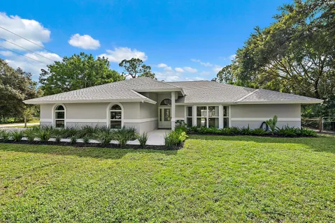 a view of a house with a yard and potted plants