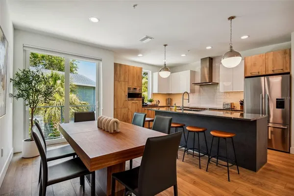 a kitchen with stainless steel appliances granite countertop a stove a refrigerator a kitchen island a table and chairs
