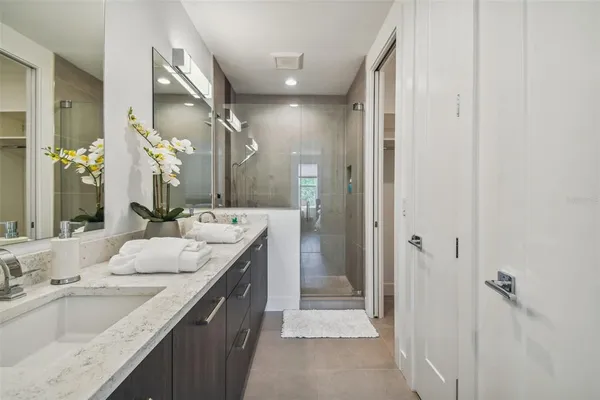 a bathroom with a granite countertop double vanity sink a mirror and a shower