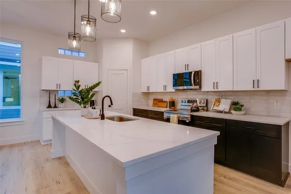 a kitchen with kitchen island granite countertop a sink a stove and cabinets