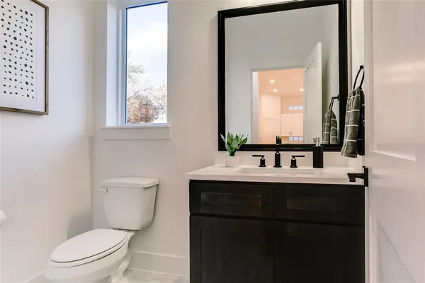 a bathroom with a toilet a sink a vanity and mirror