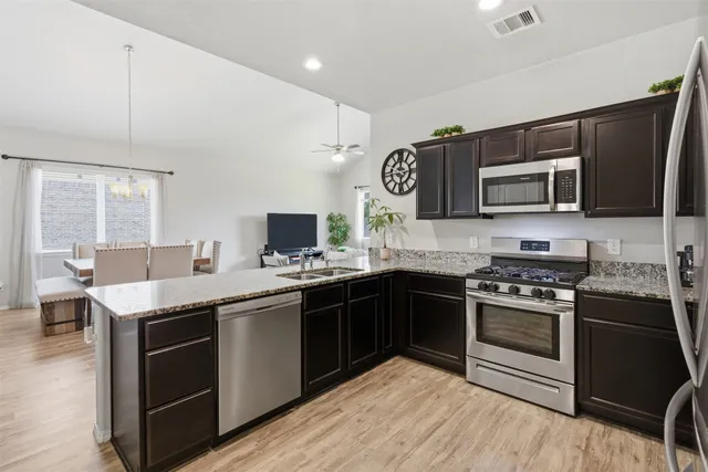 a kitchen with stainless steel appliances granite countertop a stove top oven a sink dishwasher and a microwave oven with cabinets