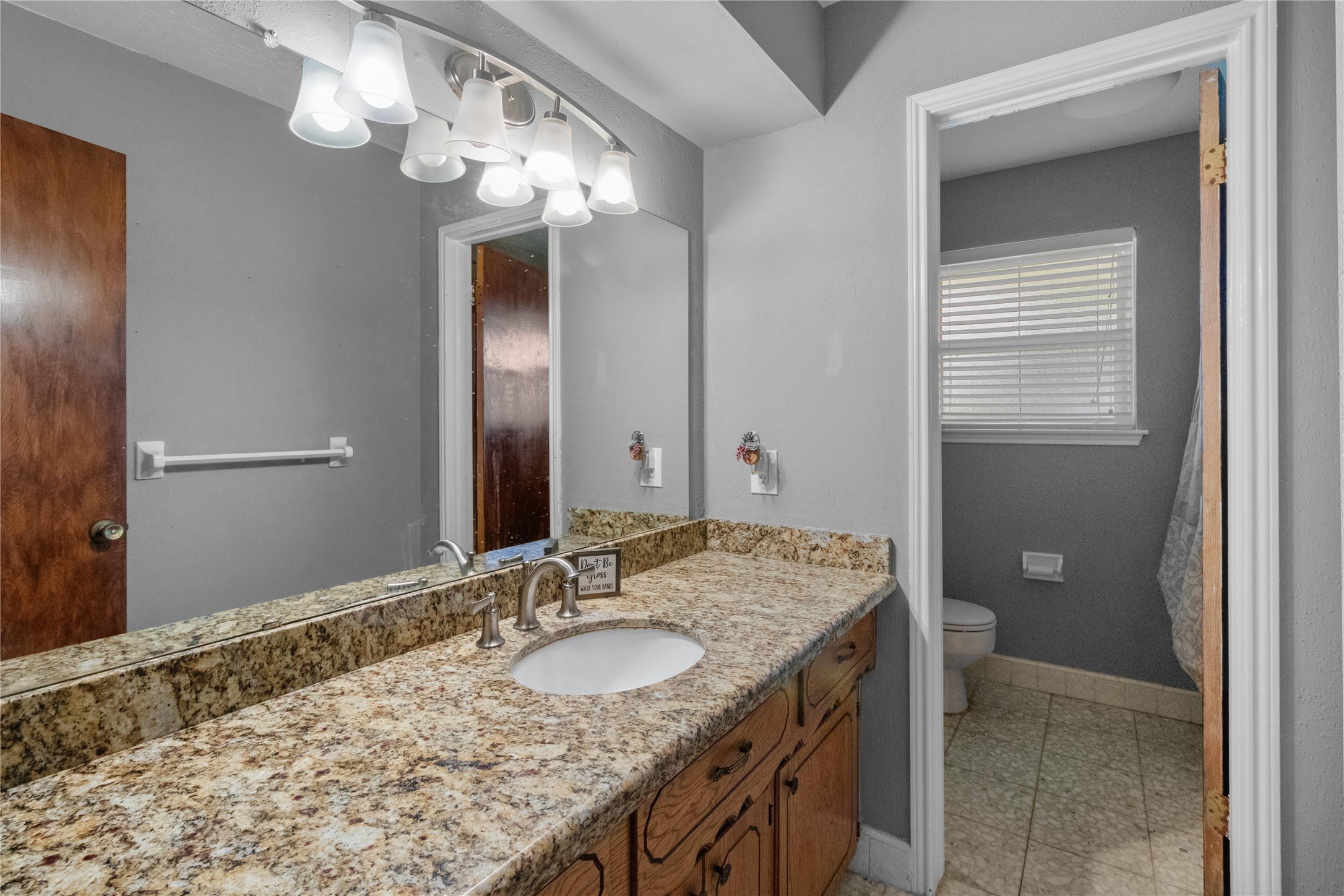 4322 Aztec Street Pasadena, TX 77504 - Photo 16 of 17 Convenience meets style in this updated secondary bathroom, featuring a granite countertop, modern lighting, and a separate shower/tub area for added functionality.