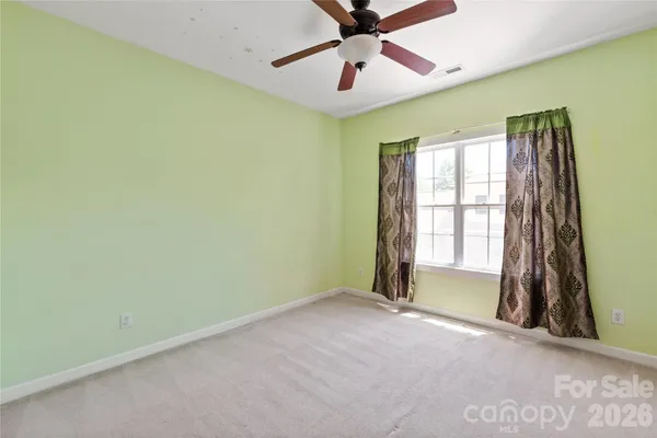 an empty room with a chandelier fan and windows