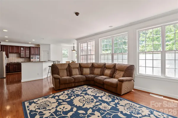 a kitchen with stainless steel appliances kitchen island granite countertop a refrigerator a stove a sink a dining table and chairs with wooden floor