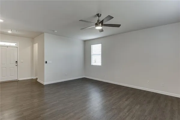 an empty room with wooden floor fan and windows
