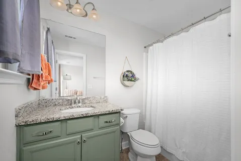 a bathroom with a granite countertop sink a toilet and a mirror