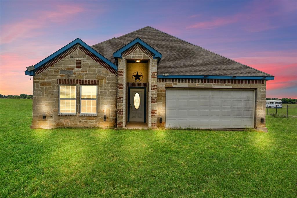 0 Ewing Road Ferris, TX 75125 - Photo 1 of 29 Stone facade home featuring a two-car garage, covered entry, and exterior lighting