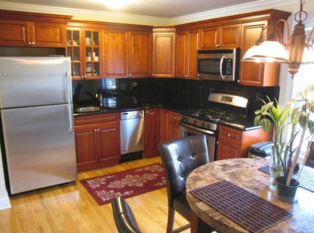 a kitchen with stainless steel appliances granite countertop a refrigerator a stove a sink a dining table and chairs with wooden floor