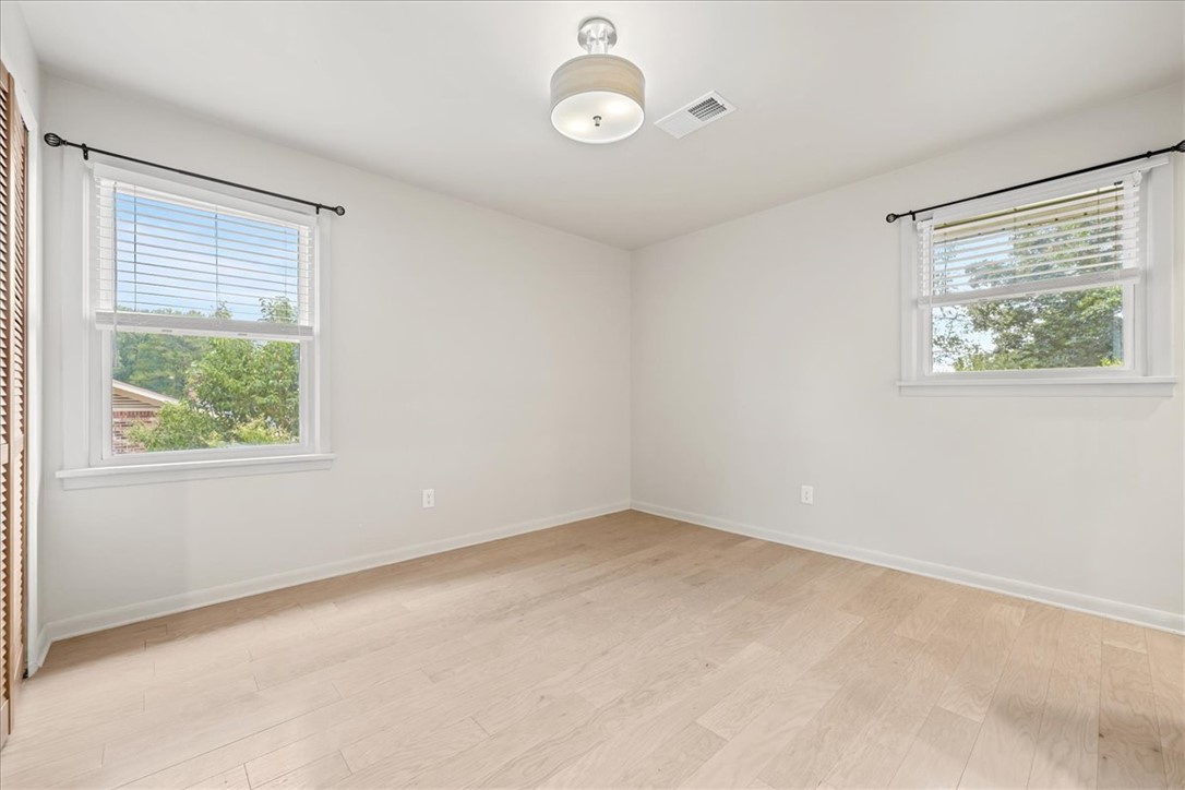 16 State Rd S-23-429 Greenville, SC 29609 - Photo 14 of 34 Hardwood floors and natural light from multiple windows define this versatile bedroom space.