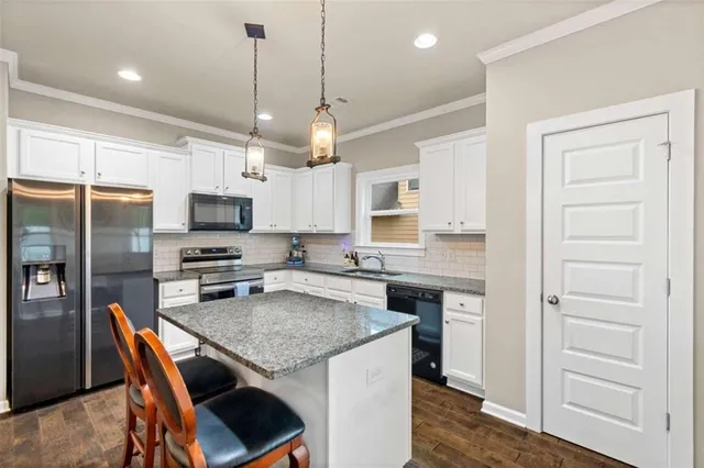 a kitchen with stainless steel appliances granite countertop a stove top oven a refrigerator a sink and chairs