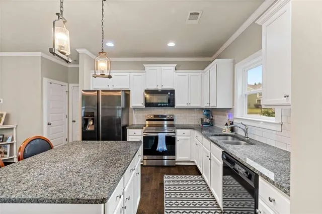 a kitchen with stainless steel appliances granite countertop a stove top oven a sink a counter space and cabinets