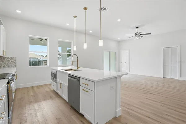 a kitchen with a stove a sink a window and wooden floor
