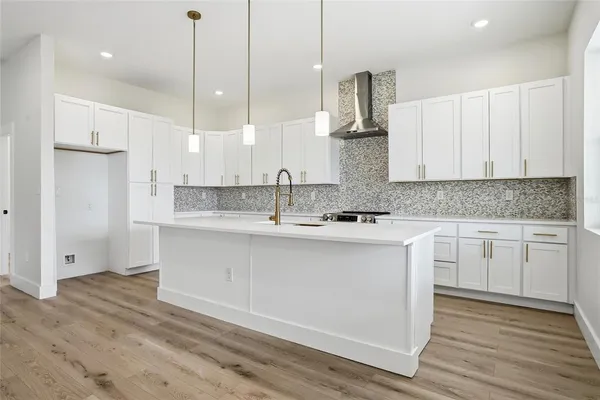 a kitchen with stainless steel appliances granite countertop a sink a stove a refrigerator and white cabinets with wooden floor
