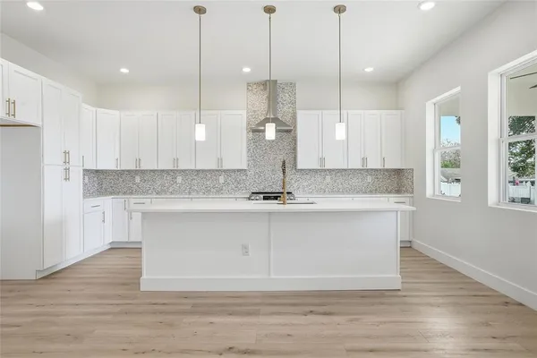 a view of a kitchen with kitchen island a sink stainless steel appliances and cabinets