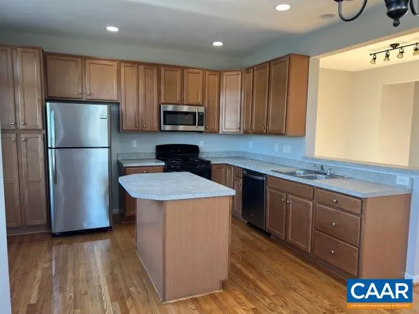 a kitchen with kitchen island granite countertop wooden cabinets a refrigerator a sink and a stove