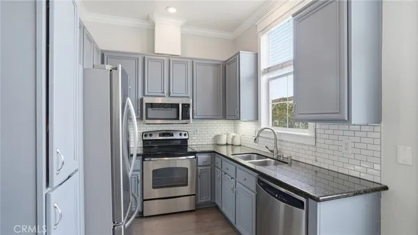 a kitchen with stainless steel appliances granite countertop a sink stove microwave and refrigerator