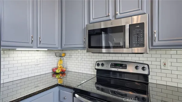 a kitchen with granite countertop cabinets stove top oven and microwave