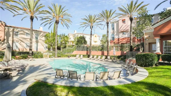 a view of swimming pool that has lawn chairs with plants and trees