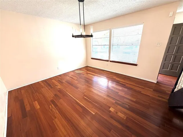 a view of empty room with wooden floor fan and window