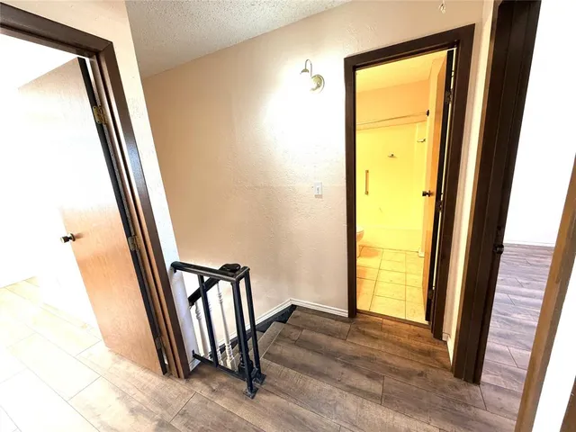 a view of a hallway with wooden floor and a door