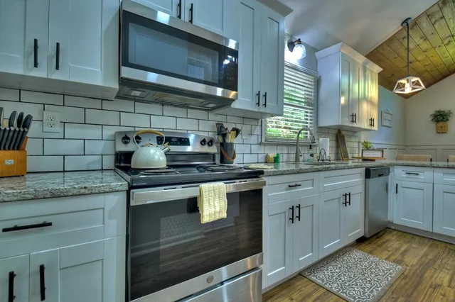 a kitchen with stainless steel appliances granite countertop a sink stove and cabinets