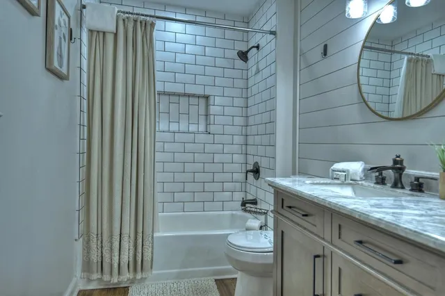 a bathroom with a granite countertop bathtub sink vanity mirror and toilet