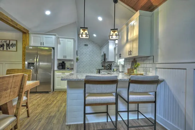 a kitchen with stainless steel appliances granite countertop a table chairs sink and wooden floor