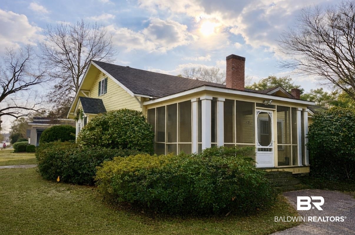 423 Evergreen Avenue Brewton, AL 36426 - Photo 3 of 18 View of home's exterior with a chimney, a sunroom, and a lawn
