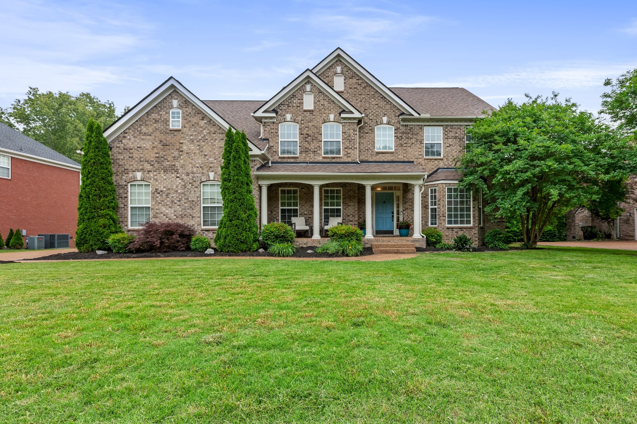 a front view of a house with a yard and trees