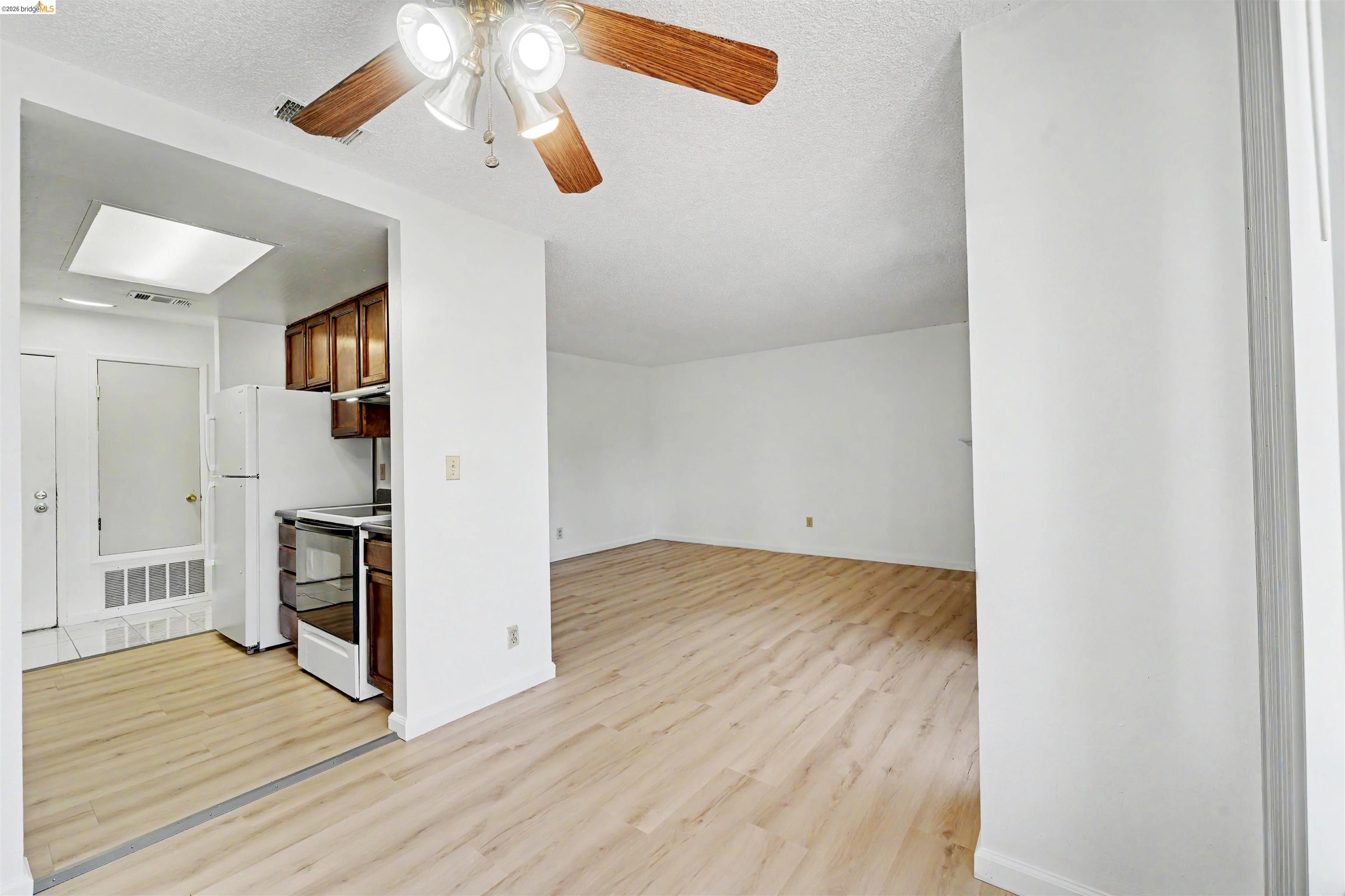4186 San Pablo Dam Road, Unit A El Sobrante, CA 94803 - Photo 24 of 34 Open-concept living space featuring wood-finish flooring throughout, a kitchen with wood cabinetry and a white appliance suite, and a ceiling fan with integrated lighting