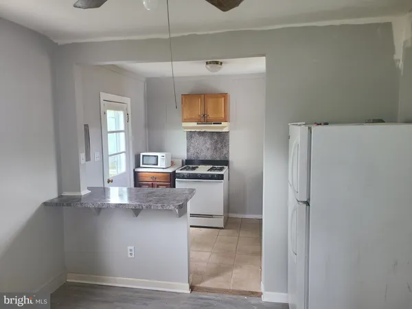 a view of a kitchen with fridge and wooden floor