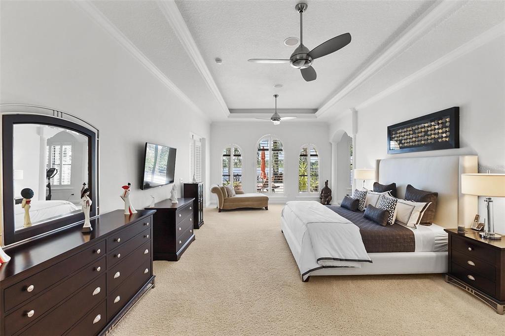 12812 Jacob Grace Court Windermere, FL 34786 - Photo 42 of 91 a spacious bedroom with a bed a mirror on dresser and a chandelier