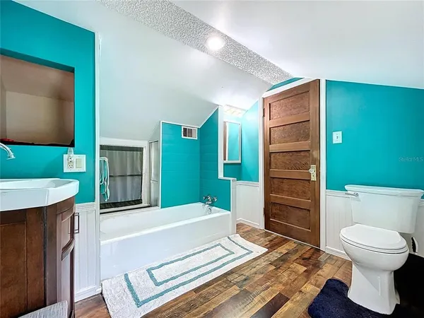 a living room with a mirror and a wooden floor