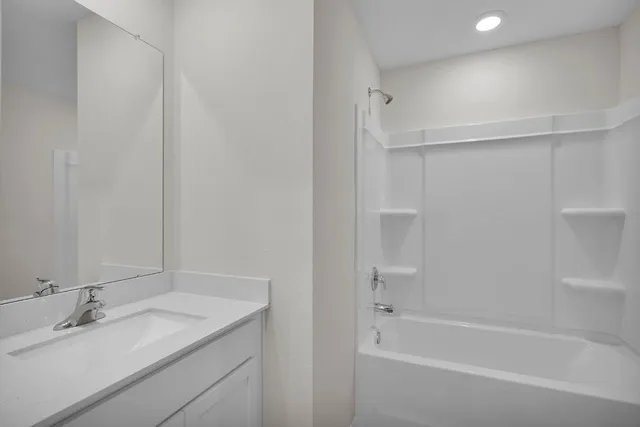 a bathroom with a granite countertop bathtub shower sink and vanity