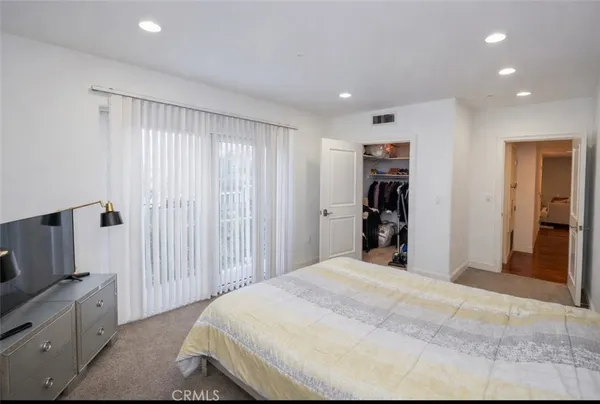 a bedroom with a large bed and a flat tv screen on dresser