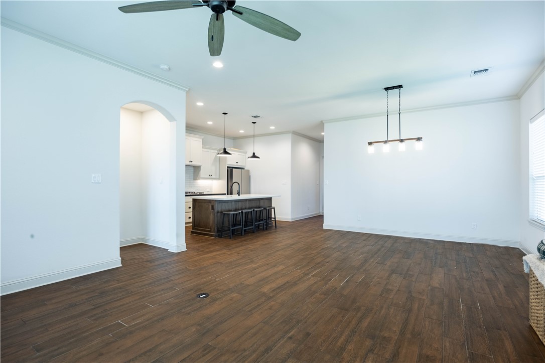 3505 Chantilly Path Bryan, TX 77808 - Photo 6 of 8 Open-concept living space featuring wood-finish tile flooring, a modern linear chandelier, and an arched entryway leading to the primary suite
